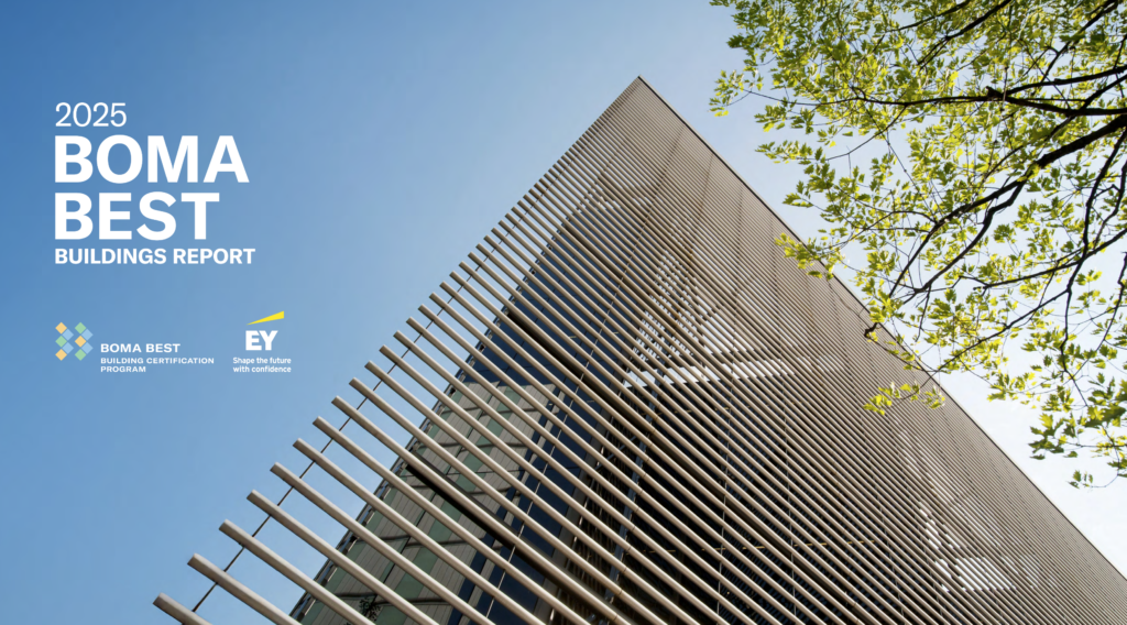 BOMA BEST - A modern building with vertical metal slats on its facade, viewed from below against a blue sky and green tree branches, featuring "2025 BOMA BEST BUILDINGS REPORT" text, highlights its BOMA BEST green building certification.